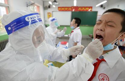 Los sanitarios toman muestras para la prueba de la covid a unos estudiantes de la escuela primaria en Handan (China).