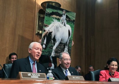 Un ayudante del senador republicano Orrin Hatch muestra una foto de un perro y un caballo durante la comparecencia de los ejecutivos de las petroleras en el Senado de EE UU.