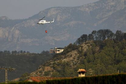 Un helicóptero sobrevuela una de las viviendas afectadas por el incendio forestal en la zona de la Marxuqera (Gandía), el 8 de agosto.