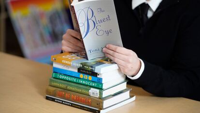 Una lectora sostiene 'Ojos azules', de Toni Morrison, sobre una pila de libros que suelen engordar la lista de los más prohibidos en Estados Unidos.