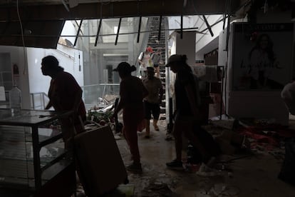 Personas toman objetos de un supermercado saqueado tras el huracán Otis.