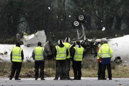 Personal del aeropuerto de Cork observa los restos del fuselaje de la avioneta que se estrelló hoy causando la muerte a seis personas