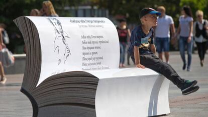 Un niño sentado en un libro gigante con un poema de Alexander Pushkin.