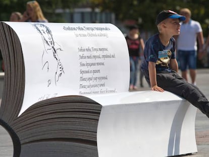 Un niño sentado en un libro gigante con un poema de Alexander Pushkin.