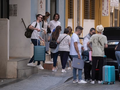 Varios jóvenes cargados con maletas salen de un piso turístico en Sevilla.