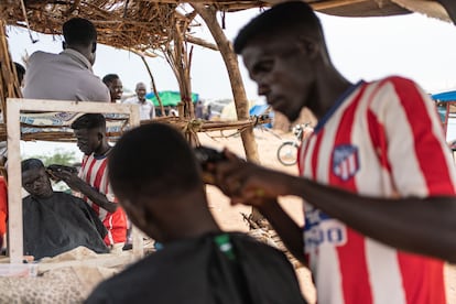 Un barbero afeita a un hombre en el mercado del campamento de Adre, el pasado 19 de septiembre. La guerra en Sudán ha disparado los niveles de inseguridad alimentaria en el país a máximos históricos.