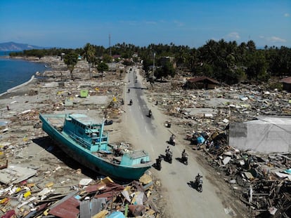 Los aldeanos circulan en motocicletas cerca de un barco arrastrado a tierra por el tsunami en Palu, el 1 de octubre.