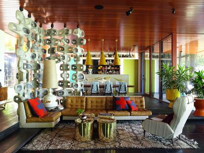 El bungaló del decorador Simon Doonan, ubicado en una isla de Nueva York muy cercana a Los Hamptons, fue diseñado por el interiorista Jonathan Adler. En la sala de esta residencia de 307 m2 el sofá, las mesillas de bronce y una pantalla de hormigón aligerado se diseñaron ex profeso. Las lámparas cónicas se encontraron en París. En otro rincón, una butaca de 1960 comprada en Palm Beach descansa sobre una alfombra de lana de Adler.