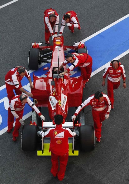 Los mecánicos de Ferrari sacan el minoplaza de Fernando Alonso, antes del entrenamiento.