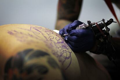 Un tatuador realiza los relieves de una figura.