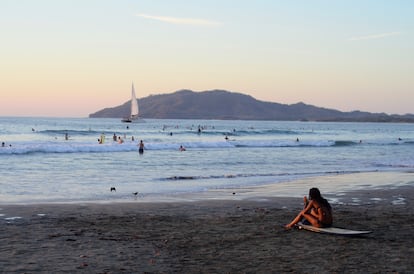 Un surfista observa el mar desde la playa. 