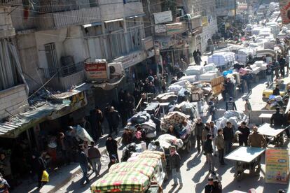 Decenas de personas junto a sus pertenencias se concentran en el puesto de control de Bustan al-Qasr, en Alepo a la espera de cruzar hacia el lado controlado por el gobierno sirio.