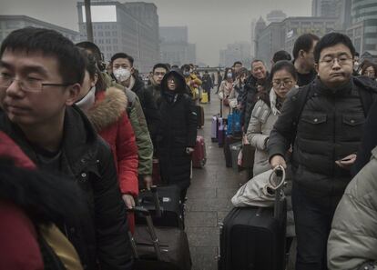 Una multitud de viajeros espera para comprar billetes de tren en la estación de Pekín.