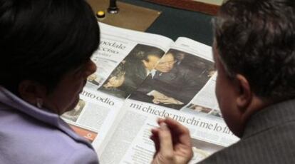 Dos diputados con un periódico que muestra la imagen de Berlusconi, ayer en el Congreso italiano.