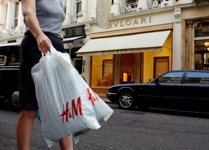 Una mujer carga con dos bolsas de la tienda H&M en Londres