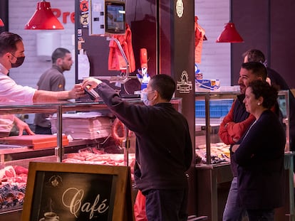 Clientes con y sin mascarilla en el interior del mercado de Triana de Sevilla.