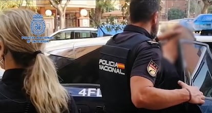 Un agente introduce a un detenido en un vehiculo policial.