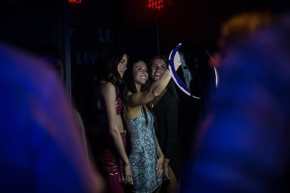 Tres amigas se toman selfies en un puesto destinado a ello en la entrada de LIV, una de las macrodiscotecas más populares en Miami. La entrada suele costar $100.