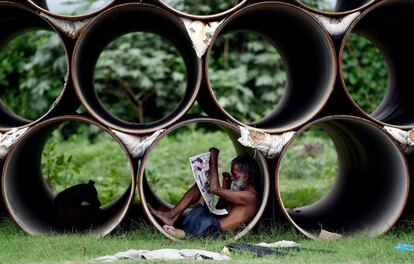 Un hombre lee dentro de un tubo en Nueva Deli, India.