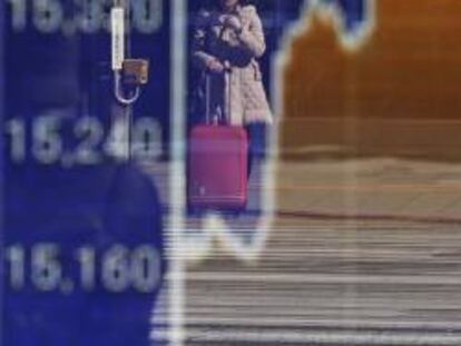 Una mujer, reflejada en un panel de cotizaciones den Tokio.