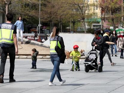 Dos policías nacionales patrullan entre niños en las calles de Madrid, este lunes. JAIME VILLANUEVA