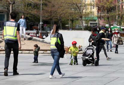 Dos policías nacionales patrullan entre niños en las calles de Madrid, este lunes. JAIME VILLANUEVA