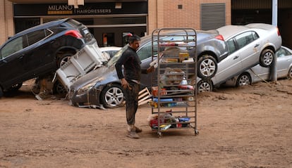 Un vecino junto a un carro con comida en una calle afectada tras el paso de la dana, este jueves en Paiporta. 