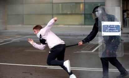  Miembros de los Mossos d'Esquadra cargan contra los centenares de personas que se agolpan ante el Aeropuerto del Prat.