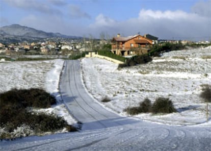 La nevada caída esta noche en la localidad de Pedrezuela, en la zona norte de Madrid, ha cubierto la carretera de la Urbanización Montenebro, haciendo necesario el uso de cadenas para transitar por ella.