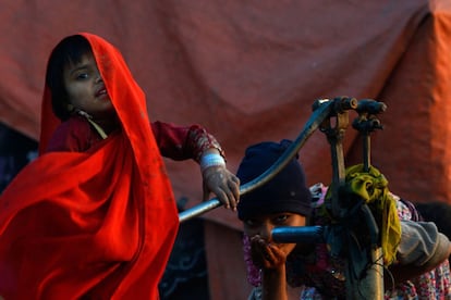 Niños gitanos paquistaníes beben agua de una bomba de mano, en Lahore.