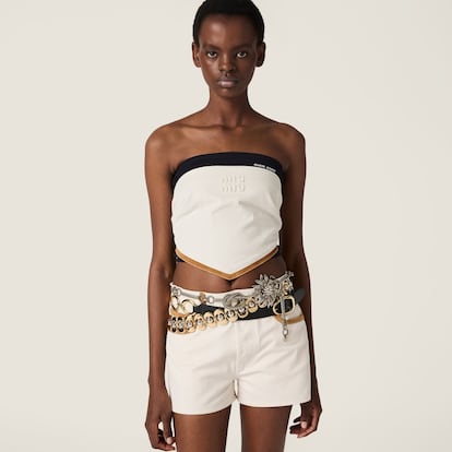 Otra referencia que no puede faltar en el imaginario 2YK son los tops bandana. Miu Miu rescata esta mítica prenda que crea el efecto de llevar un pañuelo anudado al cuerpo y lo actualiza con tejido denim y detalles en ante. (1.350 euros) 