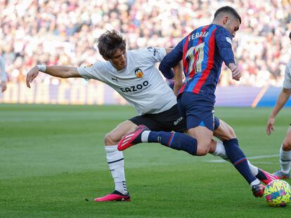 Barcelona's Ferran Torres, front, and Valencia's Jesus Vazquez compete for the ball during Spanish La Liga soccer match between Barcelona and Valencia at the Camp Nou stadium in Barcelona, Spain, Sunday, March 5, 2023. (AP Photo/Joan Monfort)