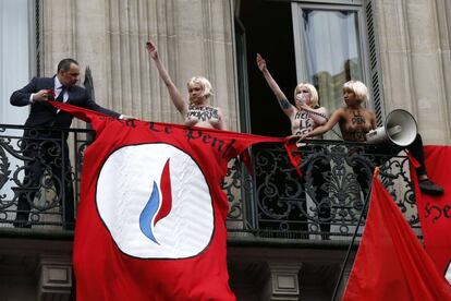 Un guardia de seguridad quita la bandera "Heil Le Pen" puesta por activistas de Femen en topless mientras realizan el saludo nazi, en un balcón contra el partido político Frente Nacional (FN) de extrema derecha de Francia durante un mitin de Marine Le Pen en honor de Juana de Arco en París.