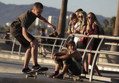 Un 'skater' realiza un ejercicio en el circuito de Venice Skatepark ante la atenta mirada de varios jóvenes.