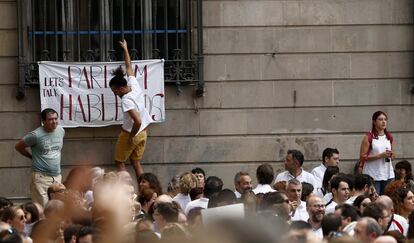 Un joven coloca un cartel a favor del diálogo en la plaza de Sant Jaume.