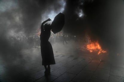Una mujer que grita consignas contra el Gobierno sostiene un paraguas rodeada por nubes de humo durante una manifestación el 10 de marzo de 2022, en Buenos Aires, Argentina. Miles de personas salieron a la calle a protestar por el acuerdo del Gobierno argentino con el Fondo Monetario Internacional para refinanciar unos 45.000 millones de dólares de deuda externa.
