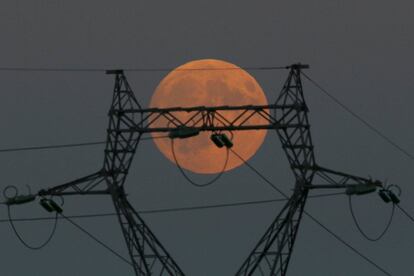 Lluna plena, l'última superlluna d'aquest any, es veu darrere d'una torre d'electricitat a Le Pallet, França.