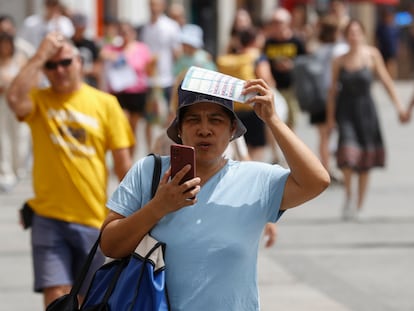 Una mujer se protege del sol mientras camina por una calle de Madrid este miércoles. España atraviesa estos días la que es, de momento, su peor ola de calor del verano.