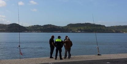 Pescadores comentan la jornada con un policía junto al Tajo, en Lisboa.