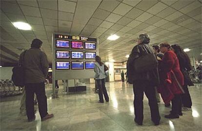 Pasajeros del aeropuerto de Barajas, el pasado sábado, ante un monitor que indicaba las cancelaciones de vuelos.