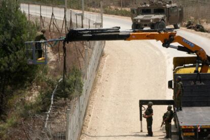 Soldados israelíes cortan un árbol sobre la valla que separa el territorio libanés y el israelí, origen del enfrentamiento fronterizo entre los dos ejércitos.
