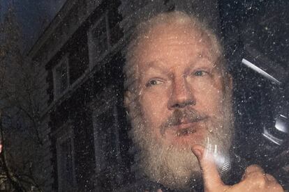 Assange saluda desde el interior del coche de policía que lo traslada, este jueves en Londres.