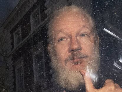 Assange saluda desde el interior del coche de policía que lo traslada, este jueves en Londres.