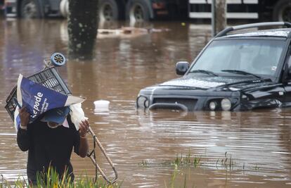 Homem se protege da chuva em via alagada de São Paulo.