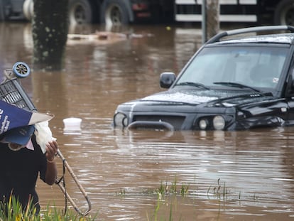 Homem se protege da chuva em via alagada de São Paulo.