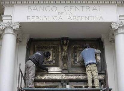 Dos operarios pulen la puerta trasera del Banco Central de Argentina, el pasado martes en Buenos Aires.