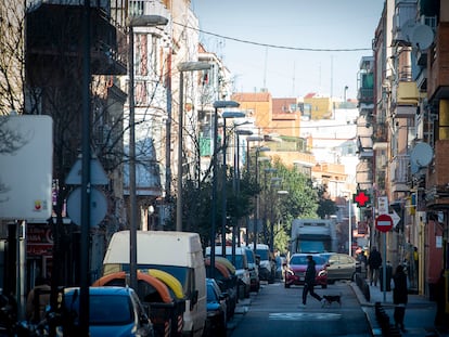 Un joven cruza la calle con un perro en la Avenida Monte Igueldo, en el distrito de Puente de Vallecas.