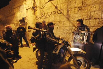 Rebeldes sirios armados se refugian en un callejón durante una manifestación el domingo en Idlib.