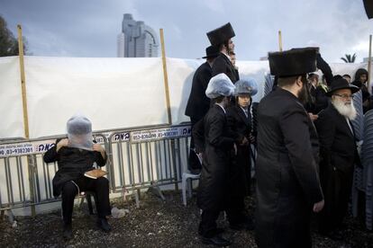 An Ultra-Orthodox Jewish man covers his hat with a plastic bag to avoid rain during the wedding of the grandson of the Rabbi of the Tzanz Hasidic dynasty community, in Netanya, Israel, Tuesday, March 15, 2016. (AP Photo/Oded Balilty) 