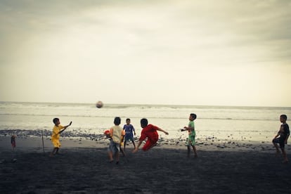 Varios niños juegan al fútbol en la playa.